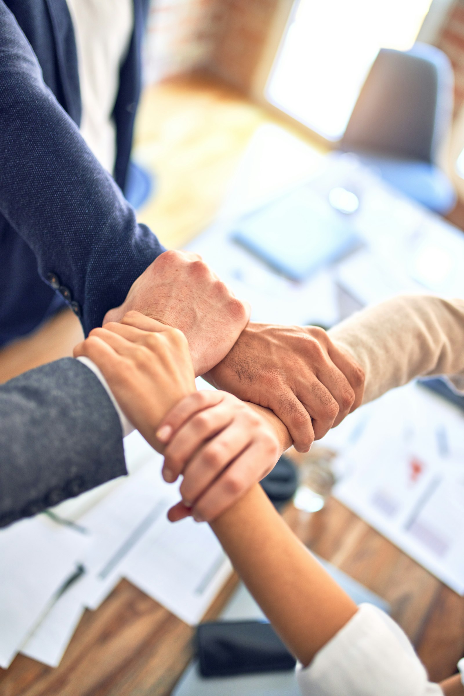 A team joining hands in unity, reflecting steady, shared leadership